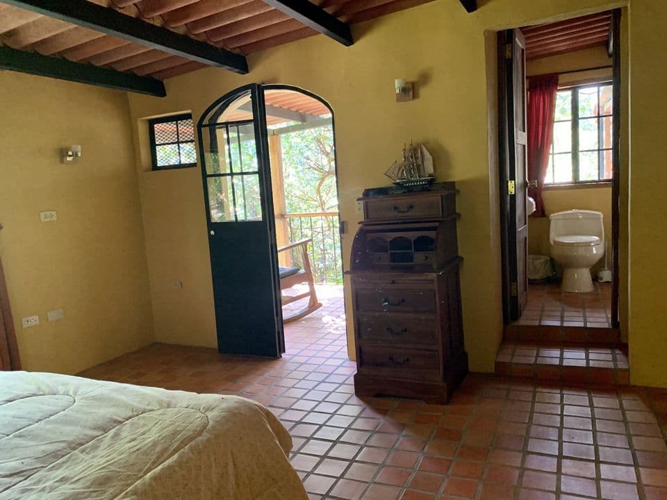 La habitación con la puerta al balcón y el baño al fondo