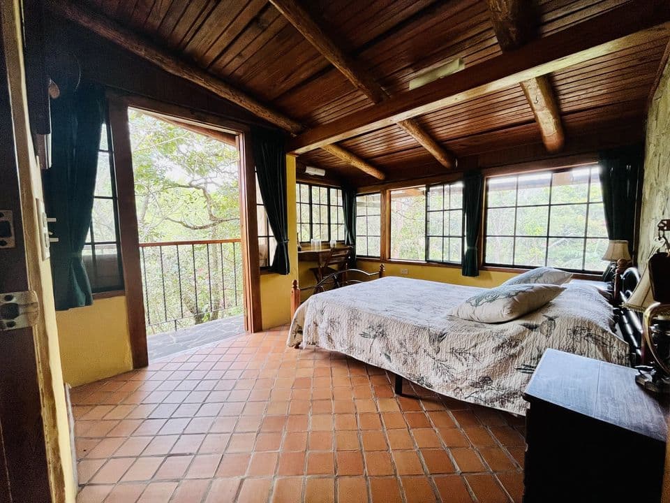 La habitación con la puerta abierta al balcón y vista al bosque