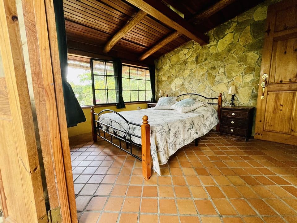 La habitación con techo de madera, pared de piedra y ventanas